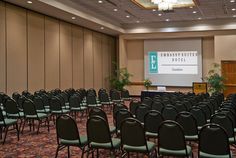 an empty conference room with rows of chairs and a projector screen on the wall