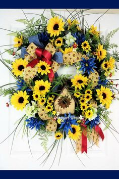 a wreath with sunflowers, daisies and bluebells is hanging on the front door