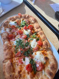 a pizza sitting on top of a white platter next to a knife and fork