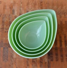 a stack of green bowls sitting on top of a wooden table