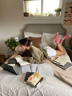 a woman laying on top of a bed covered in books