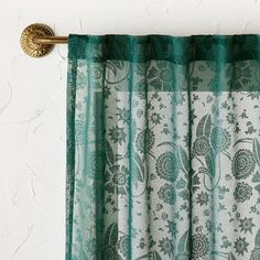 green and white curtains hanging on the side of a wall next to a gold curtain rod