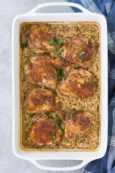 chicken and rice casserole with parsley in a white dish on a blue towel