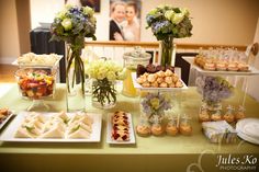 a table topped with lots of desserts and flowers next to a vase filled with flowers