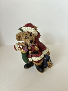 a small figurine of a teddy bear dressed as santa clause holding a bell