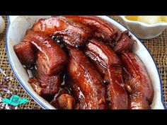 a bowl filled with cooked meat next to other dishes and utensils on a table