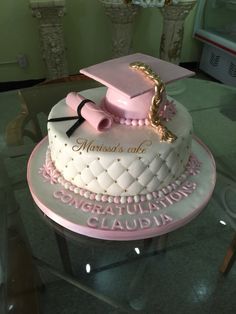 a cake that is sitting on top of a glass table with a graduation cap and tassel