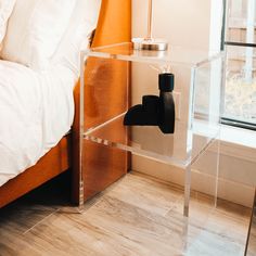 an acrylic table with a lamp on it in front of a bed