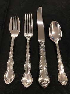 an assortment of silverware including forks, knives and spoons on a black cloth