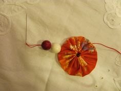 a piece of cloth with an orange and white flower on it next to a red ball