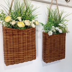 two wicker baskets with flowers in them hanging on the wall next to each other