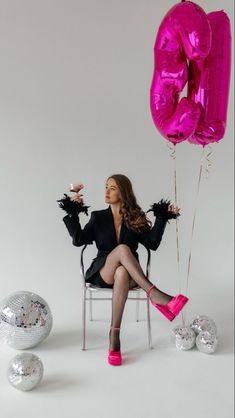 a woman sitting in a chair with balloons