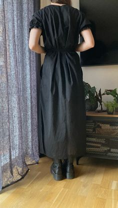 a woman standing in front of a tv wearing a black dress