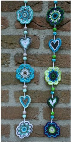 the beaded flowers are hanging on the wall next to the brick wall, which is decorated with blue and green beads