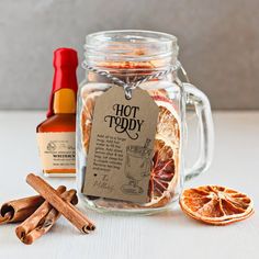 an orange slice, cinnamon and spices sit in front of a glass jar with a label on it