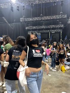 a group of people standing in front of a stage wearing black t - shirts and masks