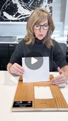 a woman sitting at a table with a piece of paper in front of her face