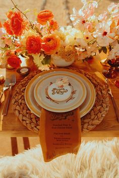 the table is set with an orange and white china plate, silverware, and flowers