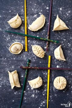 some dumplings and chopsticks are on a black surface with white stuff around them