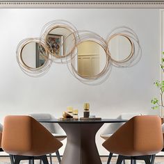 a dining room table with four chairs and a round mirror on the wall above it