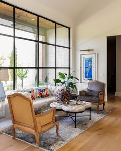 a living room filled with lots of furniture and large glass windows over the top of it