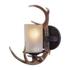 a light that is on the wall with antlers around it and a candle in front of it