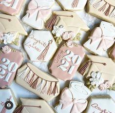 decorated cookies are arranged on a table for a baby shower or graduation party, with pink and white icing