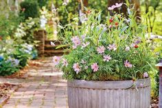 a potted planter filled with pink flowers on a brick walkway in a garden