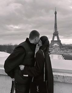 a man and woman standing next to each other in front of the eiffel tower