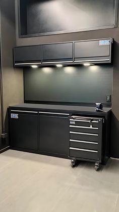 a black tool cabinet sitting in the middle of a room next to a wall mounted tv