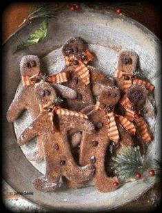 gingerbread cutouts in the shape of people on a plate with holly and pine cones