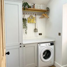 a washer and dryer in a small room with white cupboards on the wall