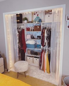 the closet is organized with clothes, shoes and handbags on shelves that are lit by fairy lights