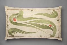 an embroidered pillow with green and red designs on the front, sitting on a gray surface