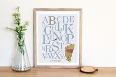 a cross stitch winnie the pooh alphabet pattern next to a vase with flowers