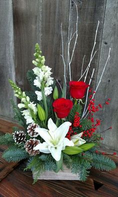 a vase filled with flowers and greenery on top of a wooden table