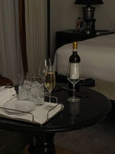 a table with wine glasses, plates and silverware on it next to a bed