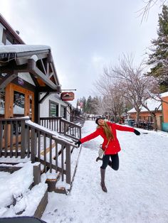 a woman in red jacket and black boots standing on snow covered steps next to building