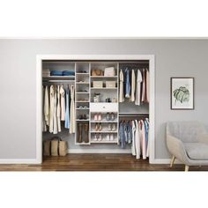 an open closet with clothes and shoes on shelves next to a gray chair in the corner