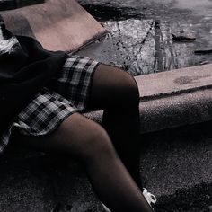 a woman is sitting on the edge of a fountain with her legs crossed and head down