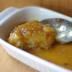 a spoon with some food in it sitting in a dish on a table next to a cup