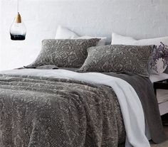 an image of a bed with grey and white comforter set on top of it