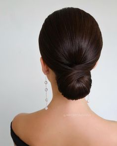 a woman with her hair in a low bun and earrings on top of her head