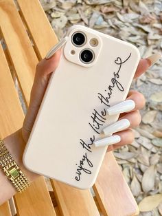 a person holding up a phone case with some writing on it and two nails attached to the back