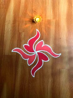 a red and white sticker sitting on top of a wooden floor next to a light