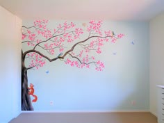 a tree with pink flowers and birds painted on it in the corner of a room