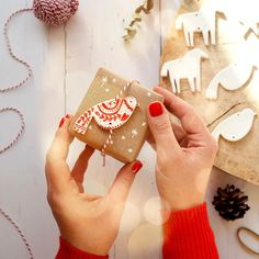 a woman holding a wrapped present in front of some christmas decorations and other holiday items