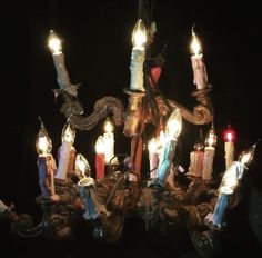 a chandelier with many lit candles in the center and an angel on top