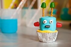 a cupcake that is sitting on top of a table with candles in the shape of a robot