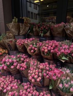 many pink tulips in brown paper bags on display outside a store front window